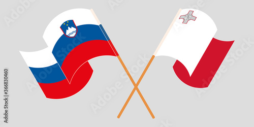Crossed and waving flags of Malta and Slovenia