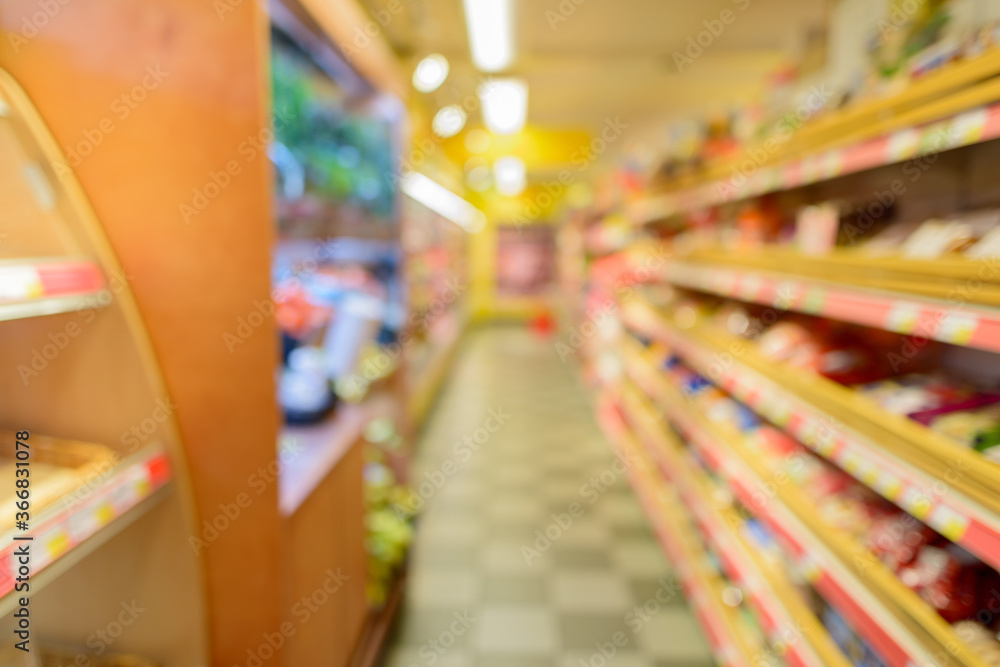 Defocused supermarket aisle with shelves filled with grocery and checkered floor Defocused supermarket aisle with shelves filled with grocery and checkered floor