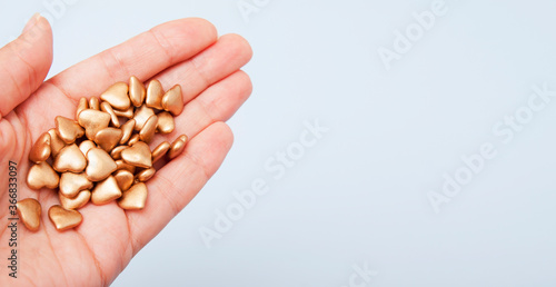 Gold hearts in hands. Concept for alms, charity, donation, fundraising with copy space