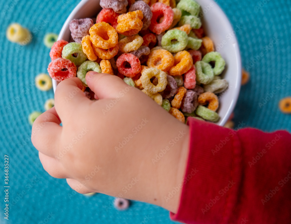Kid touching colorful breakfast cereal Kid touching colorful breakfast cereal