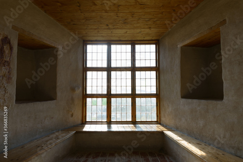 Portrait of closed wooden window and ceiling with sunlight streaming in