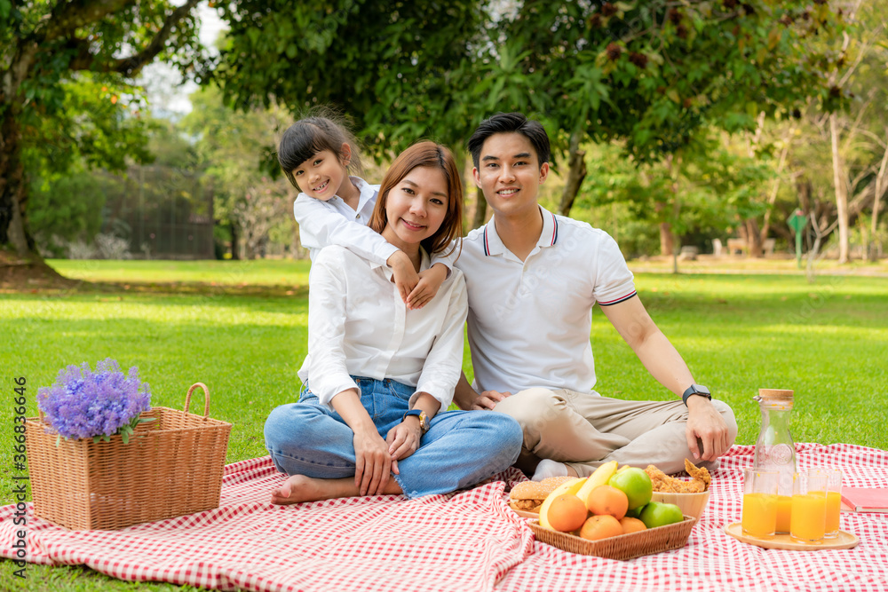 Asian teen family happy holiday picnic moment in the park with father, mother and daughter looking at camera and smile to happy spend vacation time togerter in green garden with fruit and food. Asian teen family happy holiday picnic moment in the park with father, mother and daughter looking at camera and smile to happy spend vacation time togerter in green garden with fruit and food.
