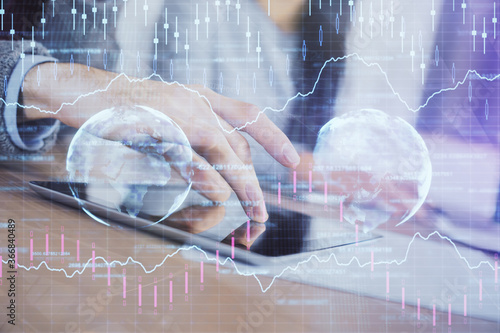 Double exposure of forex graph drawing and man and woman working together holding and using a mobile device. Trade concept.