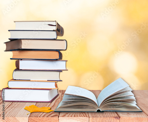 stack of books with open book and maple leaf on the wood table