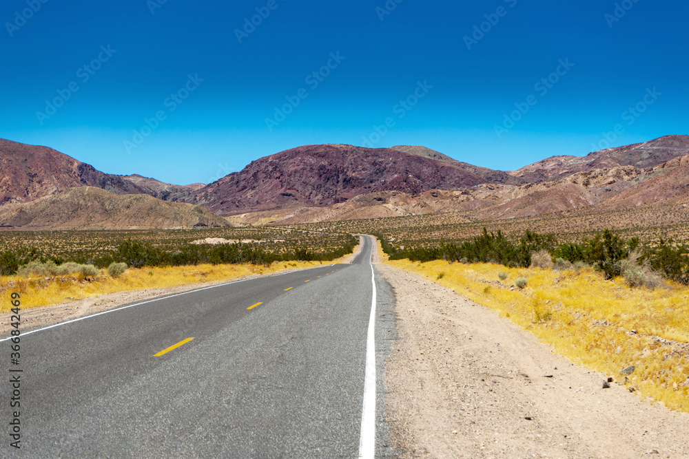 View of Calico Road without any cars north of Barstow, California, looking towards the mountains of Odessa Canyon in the Mojave Desert. 