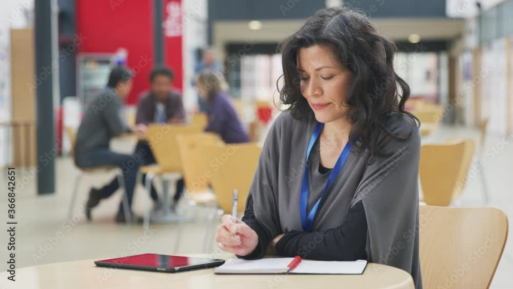 Mature female teacher or student with digital tablet working in college hall - shot in slow motion Mature female teacher or student with digital tablet working in college hall - shot in slow motion