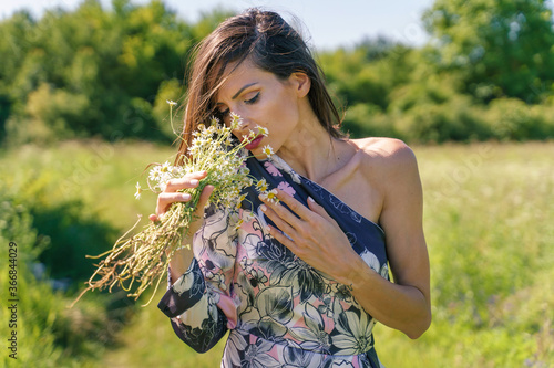 Portrait of beautiful caucasian woman in summer dress with eyes closed standing or walking in nature - Female in her 30s with hand on flowers in sunny day in the field - Emotion choice despair concept