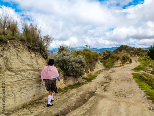 A local Ecuadorian woman walks a path in the mountains
