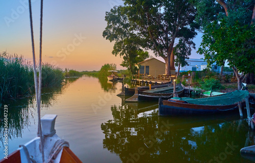 Fototapeta Naklejka Na Ścianę i Meble -  Sunset on the Albufera Canal boats in El Palmar in Valencia Spain