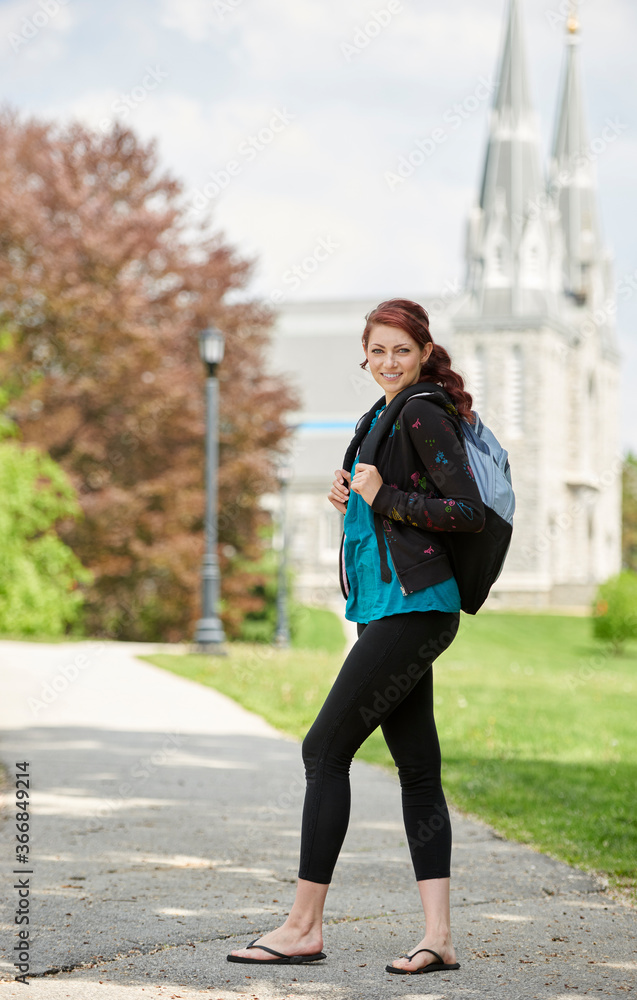 Beautiful female student, with red hair, wearing backpack on campus Beautiful female student, with red hair, wearing backpack on campus