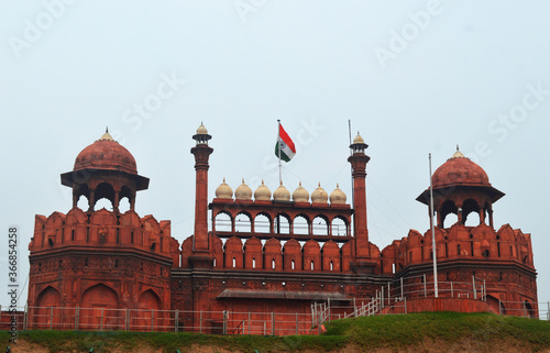 Indian National tricolor flag rising high on ancient Historic Red fort of Delhi, India