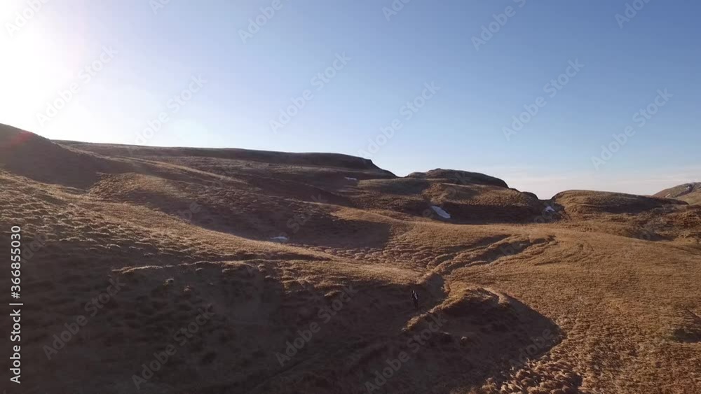 Drone shot of a man in the suit running in the grassland in Iceland Drone shot of a man in the suit running in the grassland in Iceland