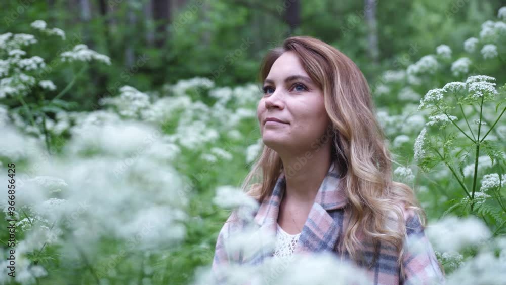 Brunette young woman in medical mask standing in green forest among white flowers, takes off protective face mask smile breathe deeply feels happy. Quarantine end, covid-19 concept Brunette young woman in medical mask standing in green forest among white flowers, takes off protective face mask smile breathe deeply feels happy. Quarantine end, covid-19 concept