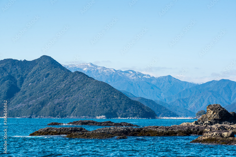 Owase bay in winter. The snow-capped mountain behind with blue sky. Owase, Mie, Japan