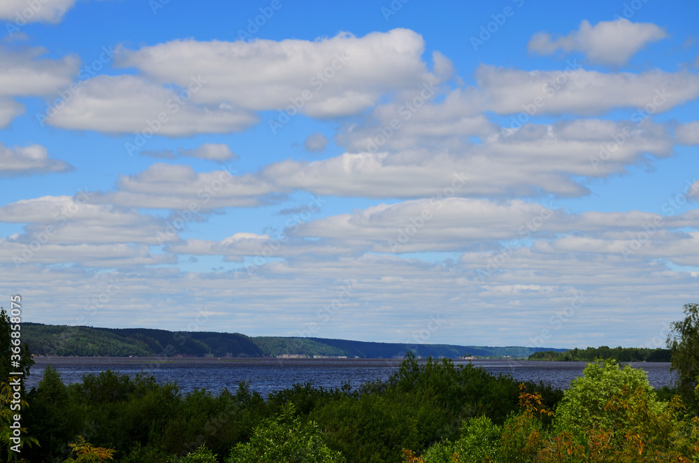 landscape wide river in the foreground of the treetops is visible to the other shore blue sky in the clouds