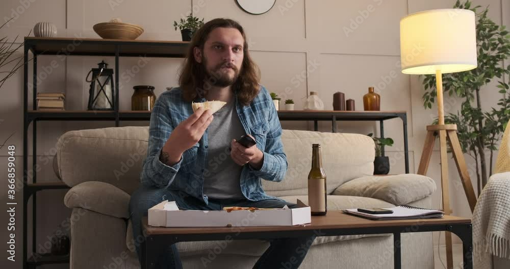 Man eating pizza and drinking beer while watching tv at home Man eating pizza and drinking beer while watching tv at home