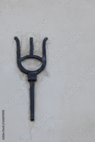 mysterious symbol reminiscent of an iron trident cast in the concrete of a house © Peter