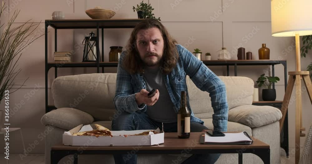 Man eating pizza and drinking beer while watching tv at home Man eating pizza and drinking beer while watching tv at home