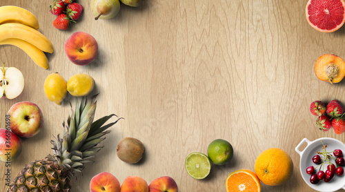 Colorful fresh fruit on wood table. Orange, strawberries, lemons, peach slice, grapefruit, limes, pears, kiwi. Summer fruit. Flat lay, top view