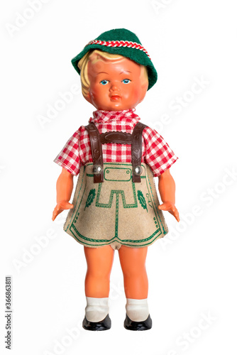 Vintage boy doll in traditional leather breeches costume with red white checkered shirt. Concept for October festival. Hard plastic celluloid figurine with felt and fabric clothes. Isolated on white.