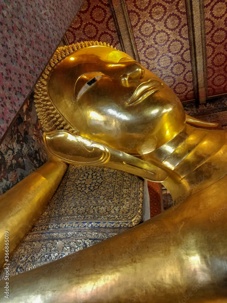 Bangkok, Thailand - January 1st 2020: Famous Reclining Buddha statue gold face. Sleeping Buddha. Wat Pho, Bangkok, Thailand.
