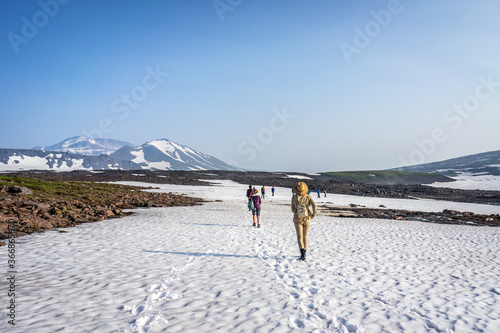 Group of hikers, tourists exploring wild nature with snowy and colourful mountains of Kamchatka 