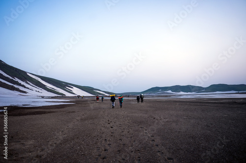 Group of hikers, tourists exploring wild nature with snowy and colourful mountains of Kamchatka 