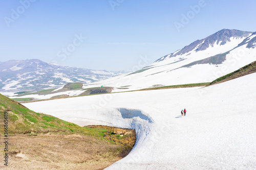 Group of hikers, tourists exploring wild nature with snowy and colourful mountains of Kamchatka 
