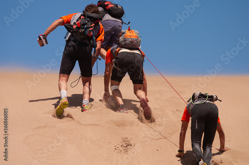 Men climbing a slope in a desert