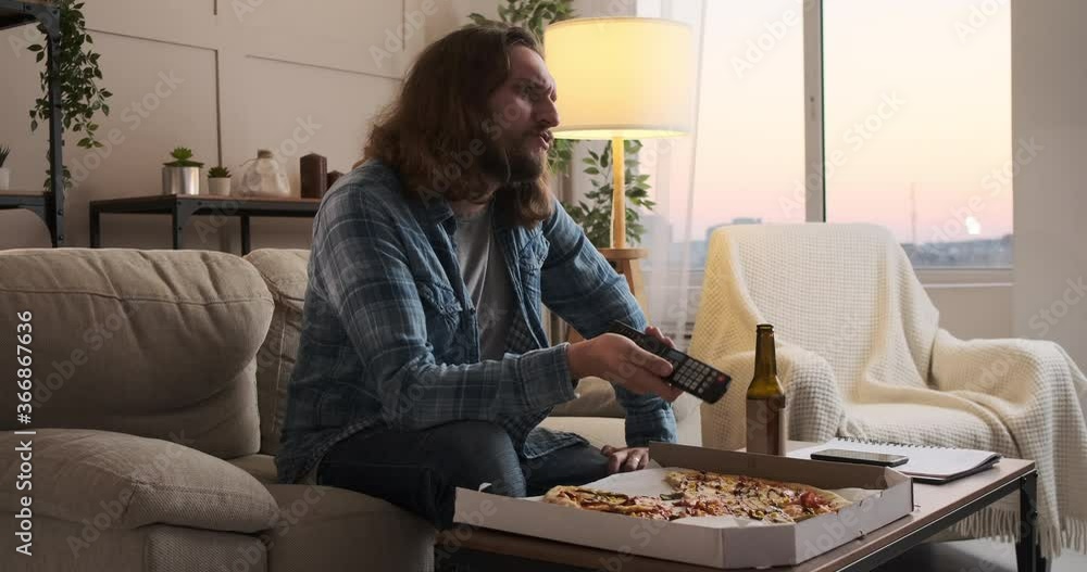 Man eating pizza and drinking beer while watching tv at home Man eating pizza and drinking beer while watching tv at home