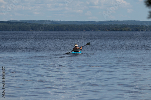 Man kayaking out into big lake on a hot summer day 