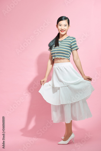Portrait of happy young beautiful Asian lady in long skirt turning around to face camera, with copy space for advertisement