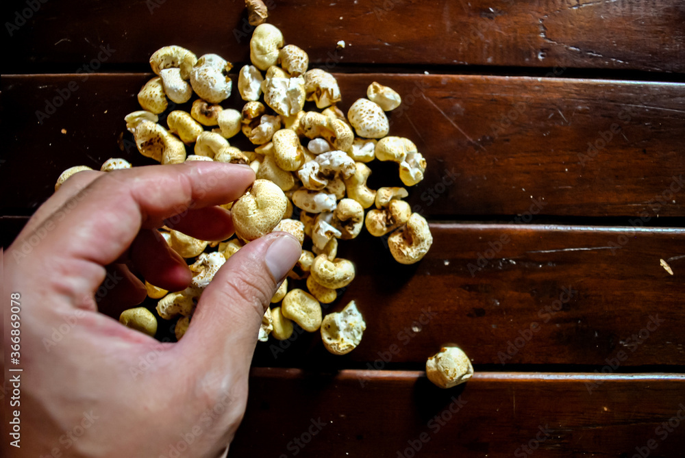 Adult hand take a popcorn on the wooden table Adult hand take a popcorn on the wooden table