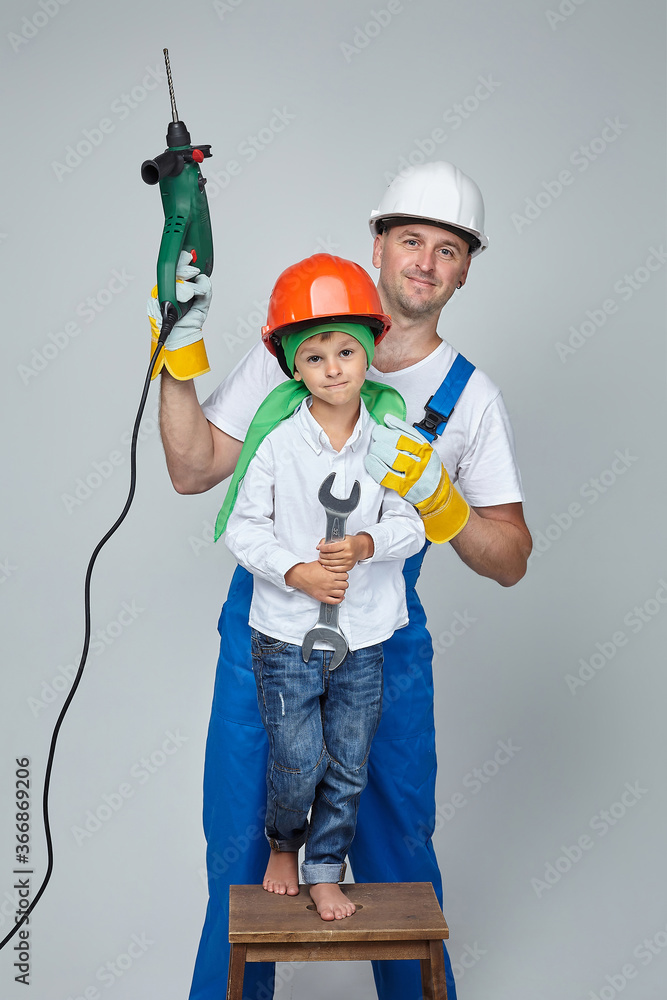 adult man with a young son in construction helmets. the concept of the construction adult man with a young son in construction helmets. the concept of the construction