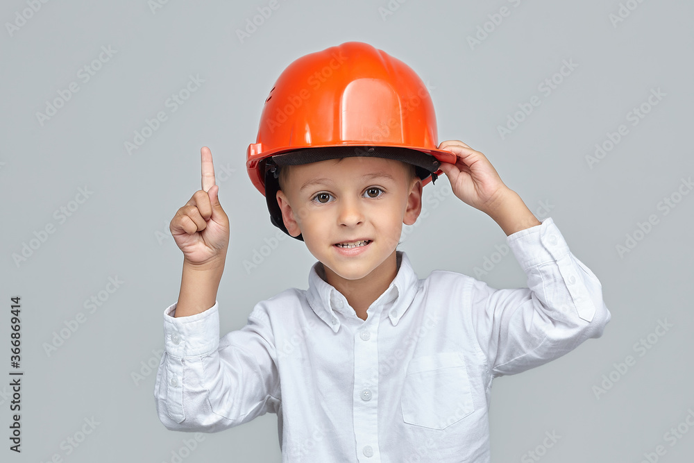 little boy in a construction helmet. the finger points in the direction of empty space. little boy in a construction helmet. the finger points in the direction of empty space.