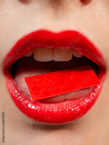 female lips, on the tongue is a red piece of paper