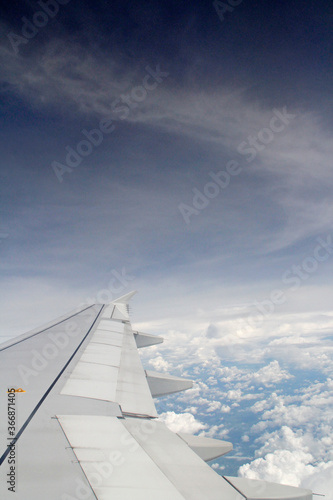 Dramatic cloudscape with the airplane's wing from the airplane's window © Crystaltmc
