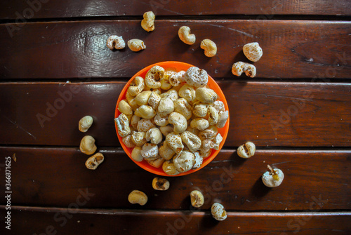 Popcorn in an orange bowl on wooden background