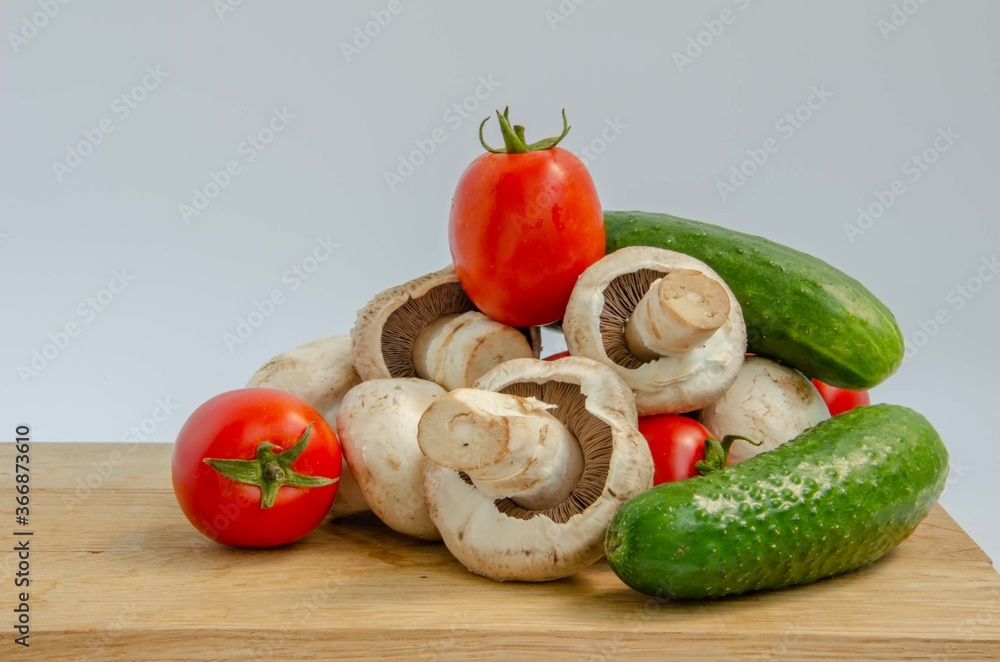 Tomatoes cucumbers mushrooms. Fresh summer vegetables and white mushrooms. Red and green vegetables background. Tomatoes cucumbers mushrooms. Fresh summer vegetables and white mushrooms. Red and green vegetables background.