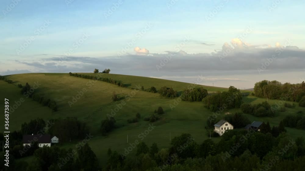 Zooming aerial 4k shot of village houses in a beautiful picturesque countryside of Dolní Morava, Czech Republic on a hill with groves and trees during a summer sunset. Summer countryside in Czechia. Zooming aerial 4k shot of village houses in a beautiful picturesque countryside of Dolní Morava, Czech Republic on a hill with groves and trees during a summer sunset. Summer countryside in Czechia.
