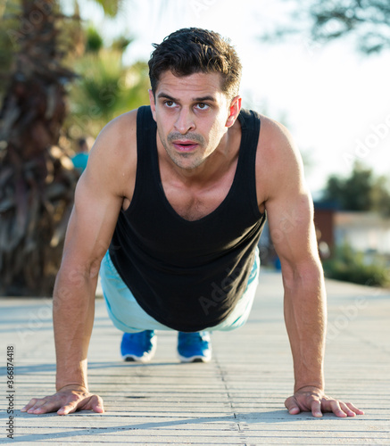 Portrait of athletic man training on beach doing press up exercises