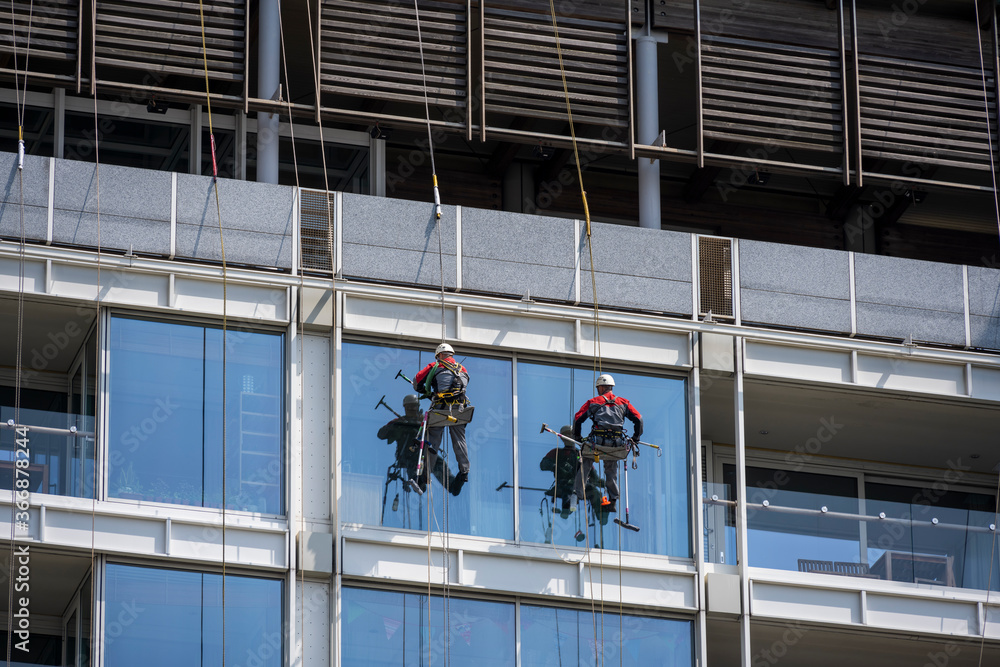 workers clean glass in a high-rise building at a height