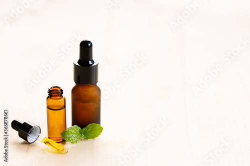 Peppermint essential oil with fresh mint leaves on wooden background