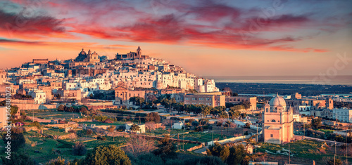 Panoramic evening cityscape of Ostuni town. Majestic summer sunset on Apulia, Italy, Europe. Traveling concept background. Beautiful world of mediterranean countries..
