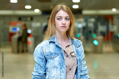 Blonde with long hair stands near the turnstiles at subway station. High quality photo