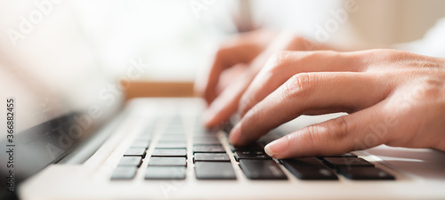 Close up hands of woman using laptop computer working and searching online information with blurry background. Technology business and social distancing concept. Panoramic banner portion