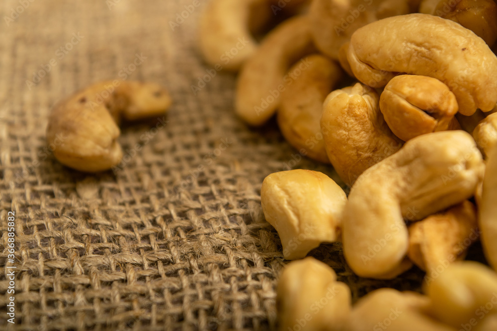 A pile of cashew nuts on burlap with a rough texture surface texture. Close up. A pile of cashew nuts on burlap with a rough texture surface texture. Close up.