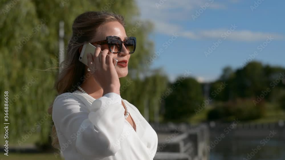 Portrait of elegant caucasian woman talking on the phone on sunny city street hd stok footage Portrait of elegant caucasian woman talking on the phone on sunny city street hd stok footage