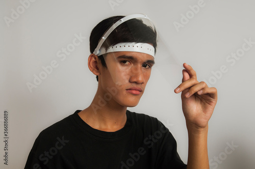 Teen Asian man wearing face shield as health protocol in new normal era for preventing corona virus / covid-19