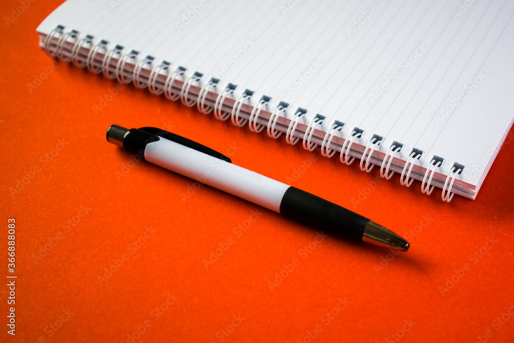 Cut out notepad with pen on orange background Cut out notepad with pen on orange background